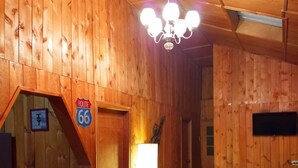 A wooden interior with a bench, a table, a wall-mounted TV, and a sign indicating Route 66.