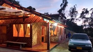 A rustic wooden building with a covered porch and a car parked in front.