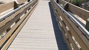 Un muelle de madera que lleva a una playa, con un embarcadero al fondo.