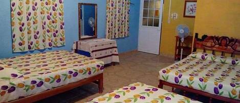A room with two beds, a mirror, a fan, and a door.