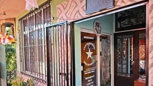 A building entrance with a metal gate, a welcome sign, and a bench outside.