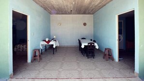 A dining area with a high ceiling, tiled floor, and two tables set for dining.