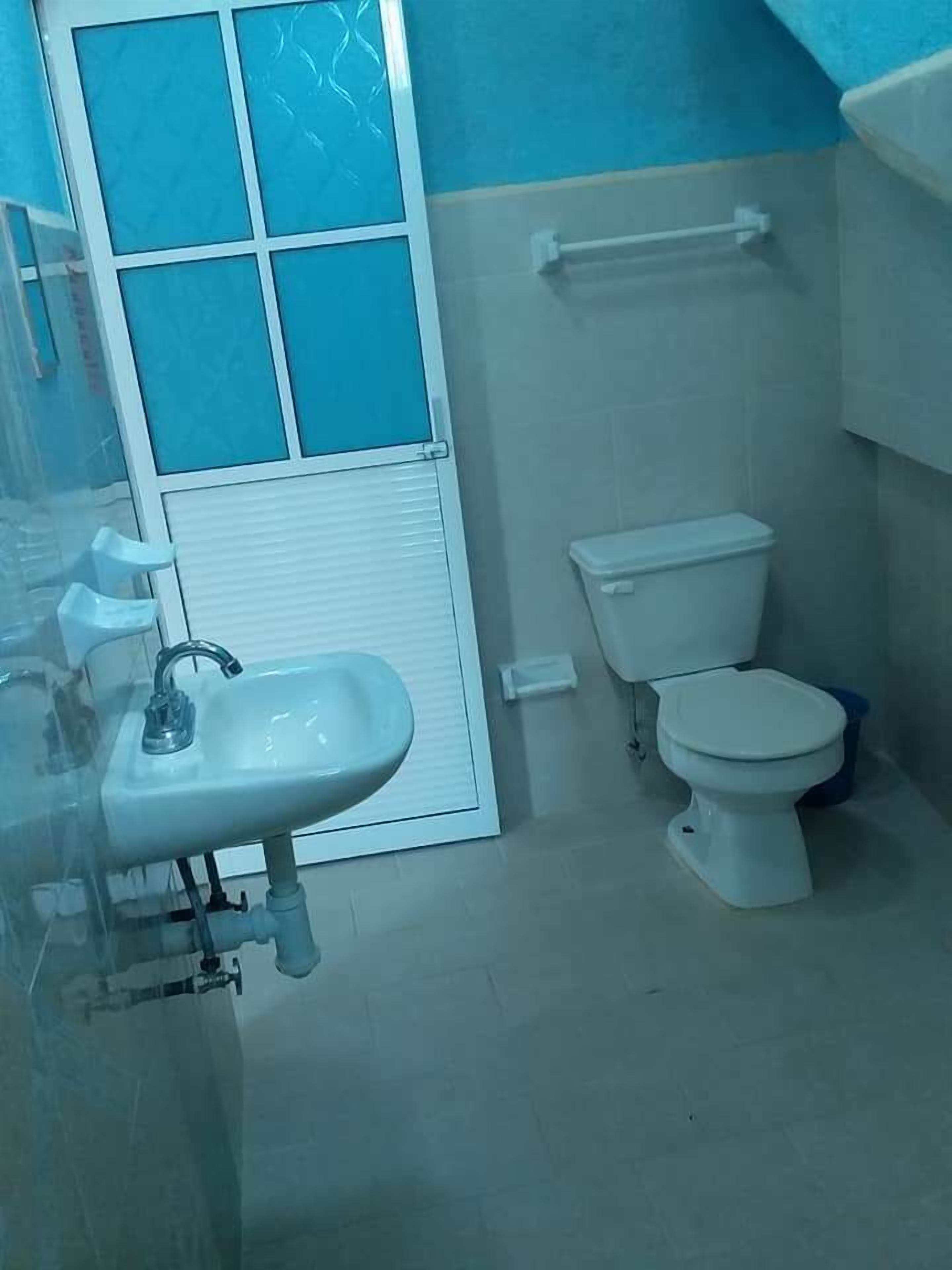 Un baño con lavabo, inodoro y ventana con diseño de celosía.