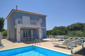 A two-story building with a swimming pool, outdoor seating, and a balcony. - Betty's Villas (Pyrgos)