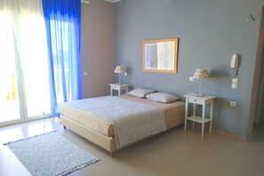 A bedroom with a bed, two bedside tables, a lamp on each table, a framed picture on the wall, and a window with curtains. - Betty's Villas (Pyrgos)