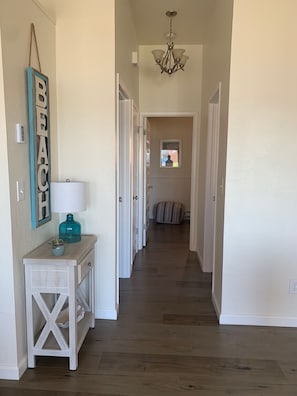 Stylish hallway leading to a serene bedroom with a console table and a framed word 'BEACH' above.