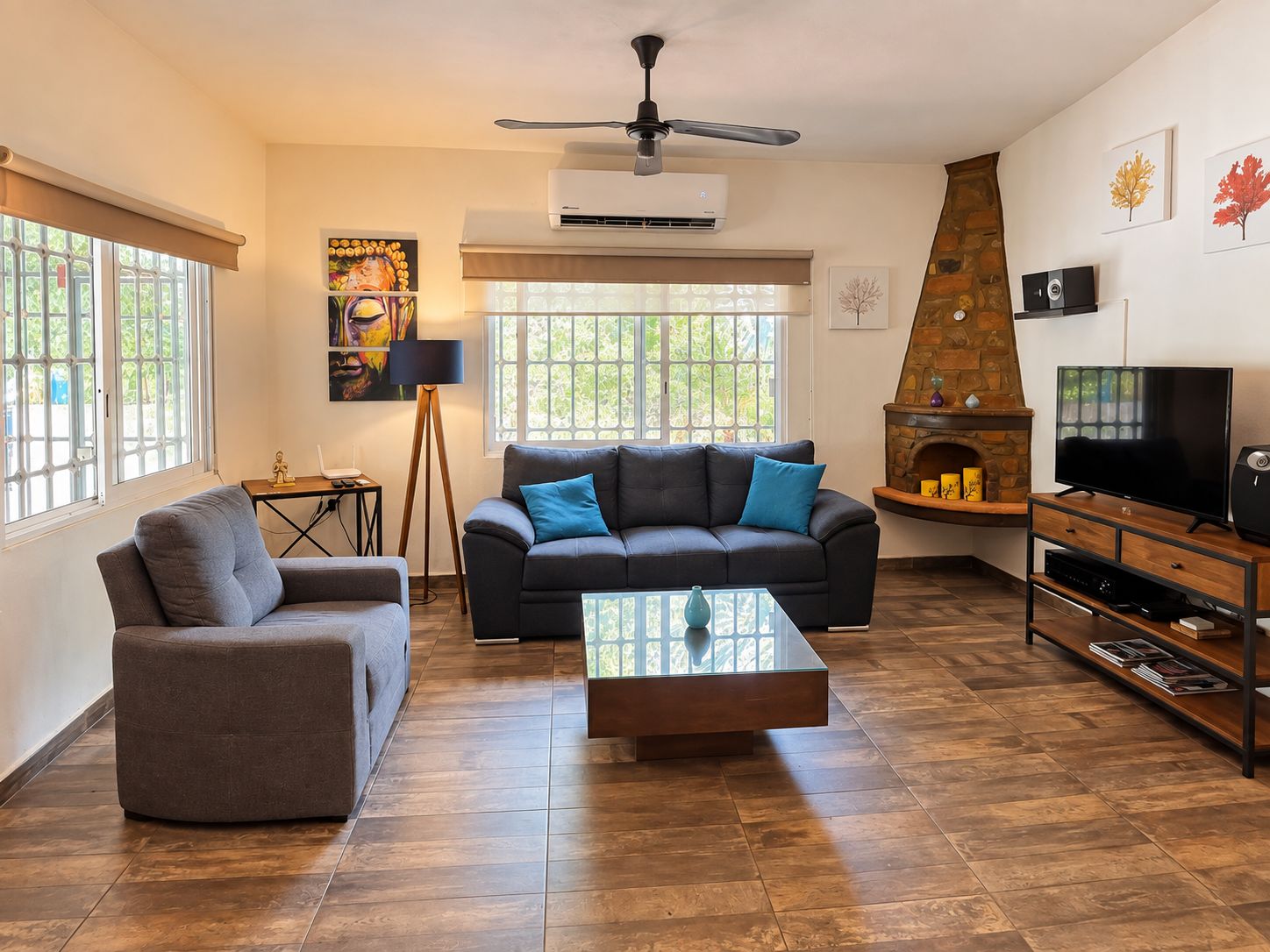Una sala de estar con sofá, sillón, mesa de centro, televisor, chimenea y obras de arte en las paredes.