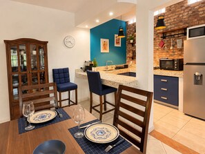 Une cuisine moderne avec un mur d’accent bleu, un coin repas avec des chaises rembourrées en bleu et un meuble encastré en bois.