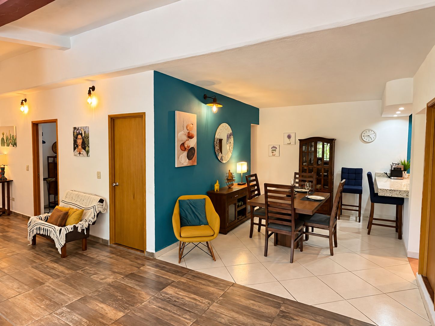 Un coin repas avec une table et des chaises en bois, un mur d’accent bleu et une horloge au mur.