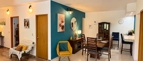 Un coin repas avec une table et des chaises en bois, un mur d’accent bleu et une horloge au mur.