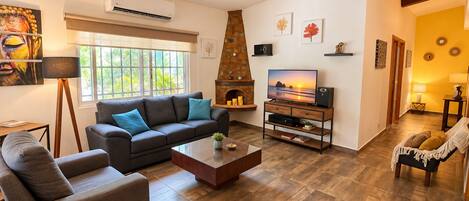 Un salon comprenant un canapé, une table basse, une cheminée, un téléviseur et un ventilateur de plafond.