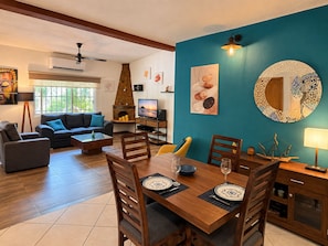 Una sala de estar con chimenea, un comedor con una mesa dispuesta para dos personas y una pared azul de acento.