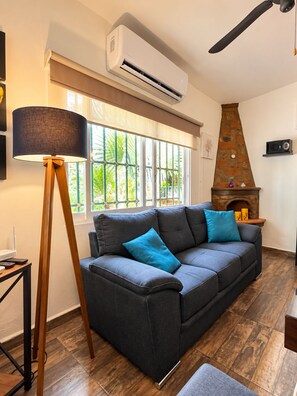 Ein Wohnzimmer mit Sofa, Lampe, Kamin und Deckenventilator.