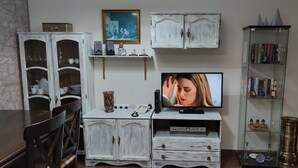 A living room with a television, white cabinets, a bookshelf, and a fireplace.