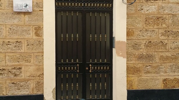 A building entrance with a numbered door, a utility box, and a bollard.