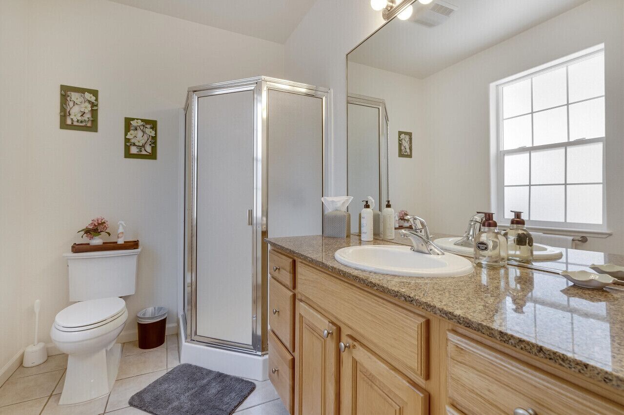 Une salle de bain moderne avec une douche à parois de verre, des toilettes blanches, un lavabo avec un meuble-vasque et un grand miroir.