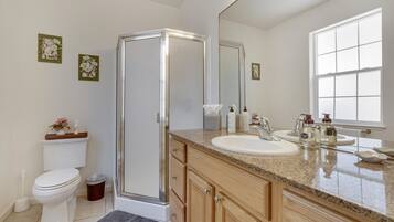 Une salle de bain moderne avec une douche à parois de verre, des toilettes blanches, un lavabo avec un meuble-vasque et un grand miroir.