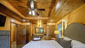 Quarto de cabana de madeira com cama, cômoda e ventilador de teto.
