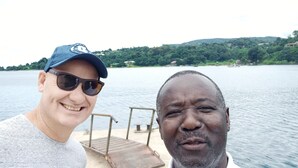 Two people on a boat with a dock and greenery in the background. - Rayoni Guesthouse B&B (Mzuzu)
