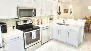 Una cocina moderna con gabinetes blancos, electrodomésticos de acero inoxidable y una isla central con un fregadero.