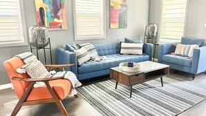 Una sala moderna con un sofá azul, un sillón naranja y una mesa de centro.