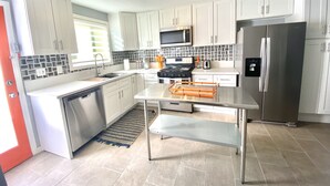 Una cocina moderna con gabinetes blancos, electrodomésticos de acero inoxidable y una isla central.