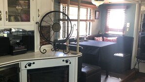A cozy room with a fireplace, a fan, and a seating area with a table and chairs.