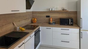 A modern kitchen with a wooden countertop, a built-in oven, a microwave, and a refrigerator. - Gorgeous apartment in Rijeka with WiFi (Rijeka)