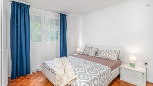 A bedroom with a bed, a nightstand, a lamp, and a window with curtains. - Gorgeous apartment in Rijeka with WiFi (Rijeka)