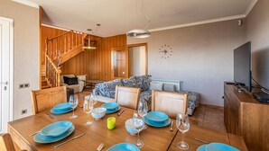 A dining area with a wooden table set for four, a sofa, and a TV on a wooden cabinet. - Beautiful home in Sant Cebrià de Vallalt (Sant Cebrià de Vallalt)