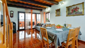 Un coin repas avec une table dressée pour quatre personnes, un canapé et un balcon agrémenté de rideaux.