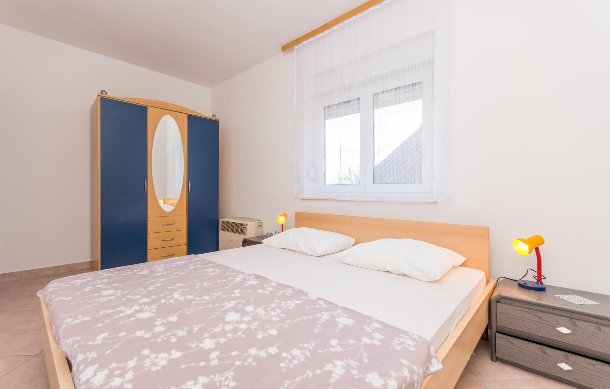 Une chambre à coucher avec un lit, une table de chevet, une lampe et une armoire.