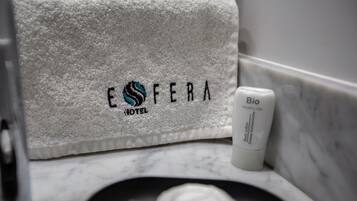 A white towel with embroidered text and logo, a white bottle labeled "Bio" on a marble surface.