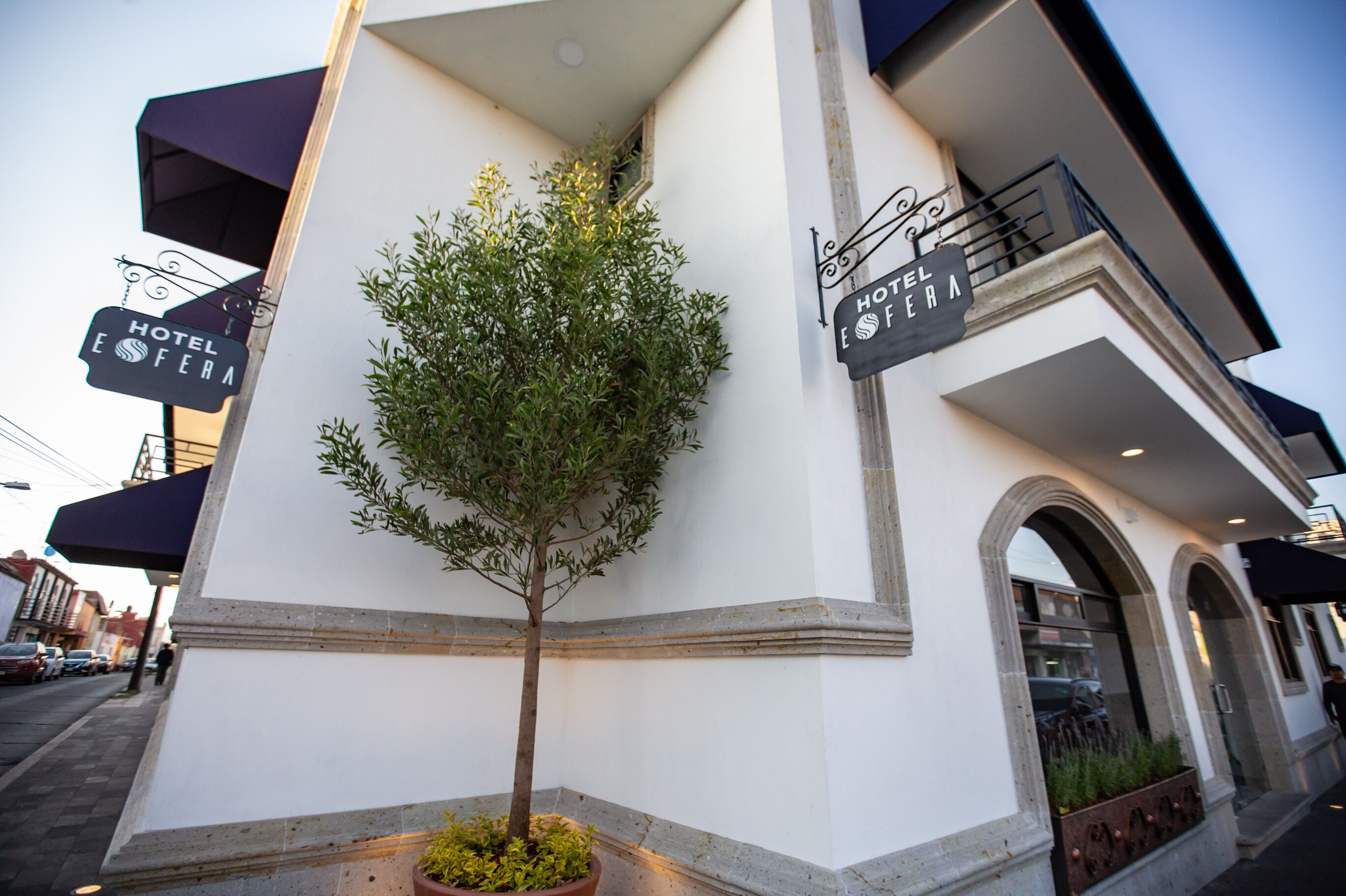 Eine Hotelansicht mit Baum, einem Schild mit der Aufschrift 'HOTEL EFERA' und einem Balkon mit Geländer.