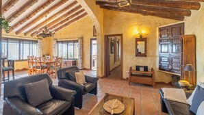 A spacious living room with leather sofas, a coffee table, and a dining area with wooden furniture. - Finca Hornillo Cómpeta by Ruralidays (Málaga)