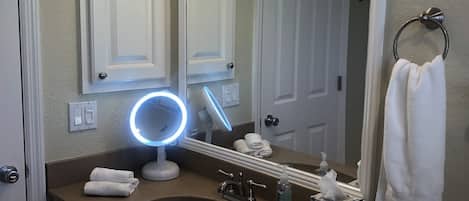 A bathroom with a vanity, sink, mirror, and three overhead lights.
