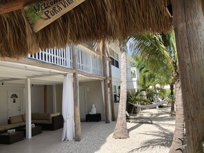 Un resort con tetto di paglia, un balcone bianco e un'amaca.