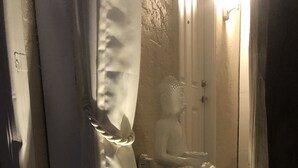 Un espacio para meditar con una estatua, un banco y una cortina.