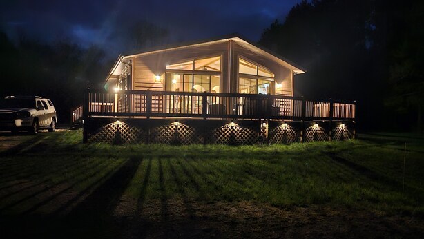 A two-story house with a deck, surrounded by a fence and a lawn. - New on market.  Cabin with 3 beds and 3 baths surrounded by forest (Grand Marsh)