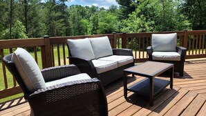 A wooden deck with wicker furniture, including a sofa and chairs, and a small table. - New on market.  Cabin with 3 beds and 3 baths surrounded by forest (Grand Marsh)