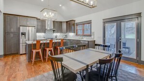A modern kitchen with a central island, stainless steel appliances, and a dining area with a large table and chairs.