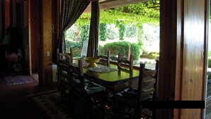 A dining area with a wooden table and chairs, a yellow bowl, and a view of greenery outside. - Villa with panoramic veranda 'Il Riccio' (MONTE ARGENTARIO)
