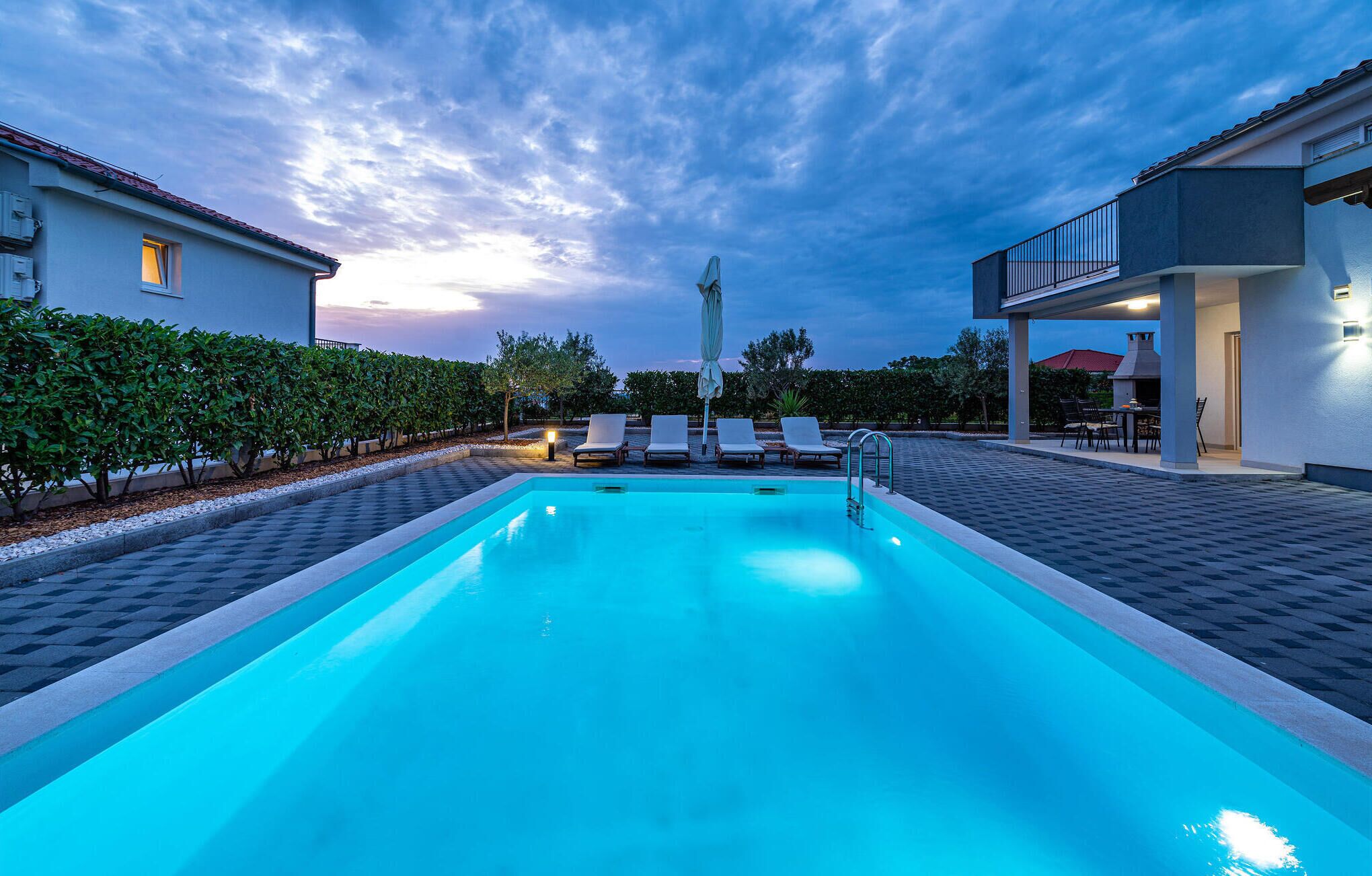 A swimming pool with lounge chairs and a covered patio area.