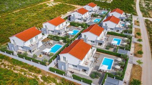Un complejo residencial con varias casas, cada una con piscina y zonas de estar al aire libre.