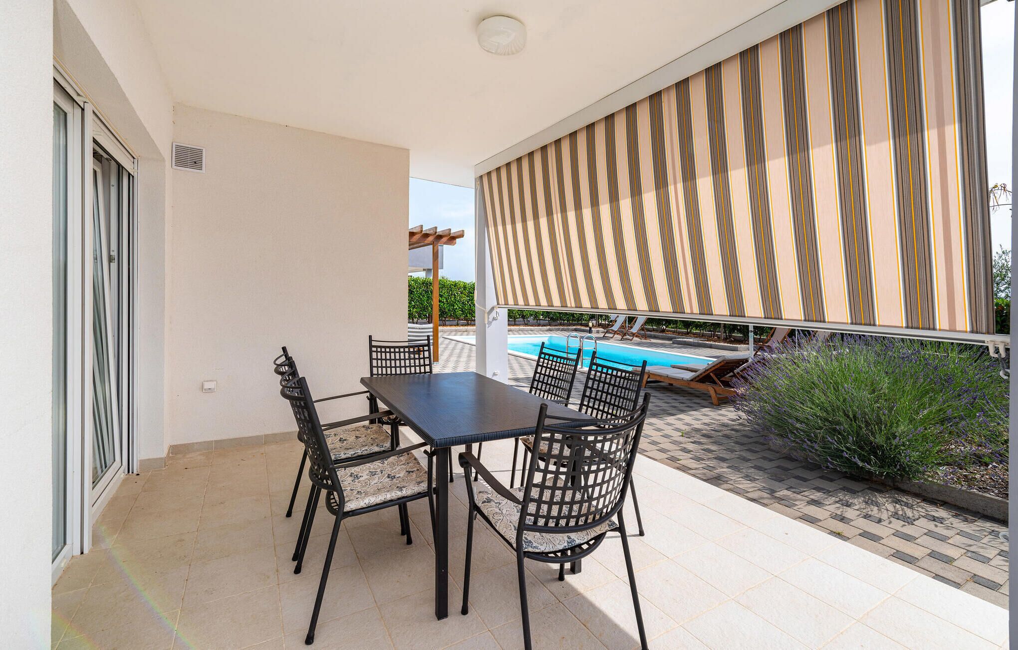 A patio with a pool, outdoor seating, and a view of the pool.