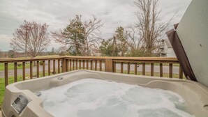 Een hottub op een balkon met houten balustrade, een gazon en kale bomen op de achtergrond.