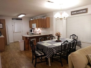 A compact kitchen with wooden cabinets, a microwave, and a dining area with a checkered tablecloth.