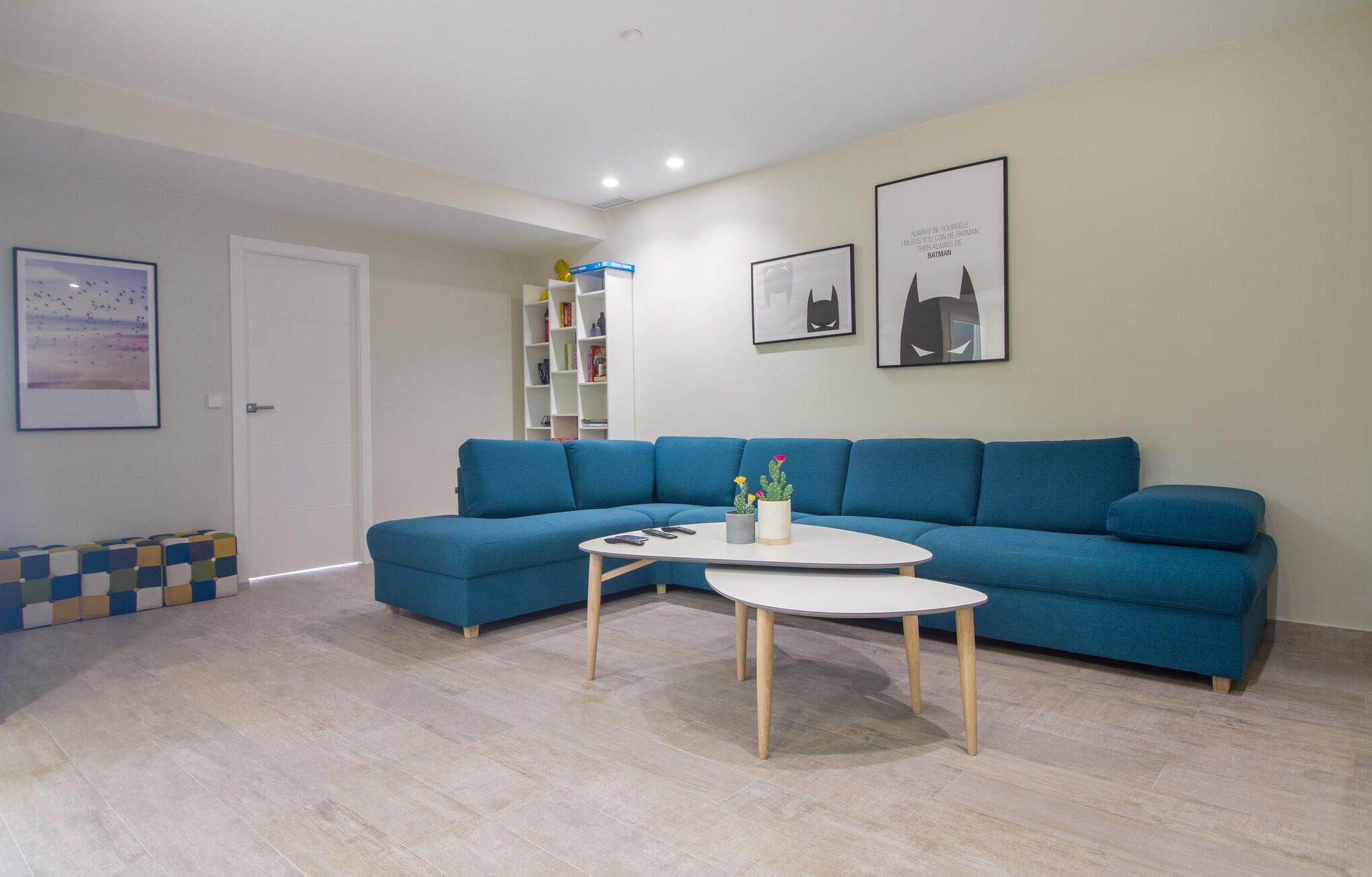 A modern living room with a blue sofa, a white coffee table, and a bookshelf.