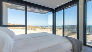 Un dormitorio con una cama grande, vistas de la ciudad y un balcón.