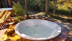 A hot tub with a wooden edge, surrounded by a fence and outdoor furniture. - Ruca Lemu (Chascomus)